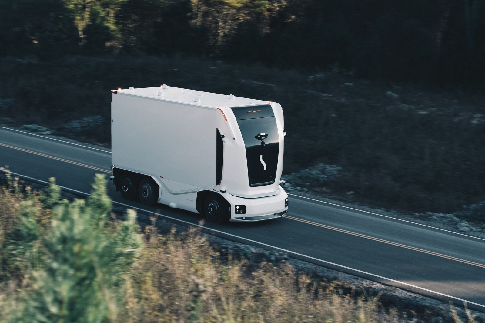 An Einride autonomous electric truck on a forest road at dusk