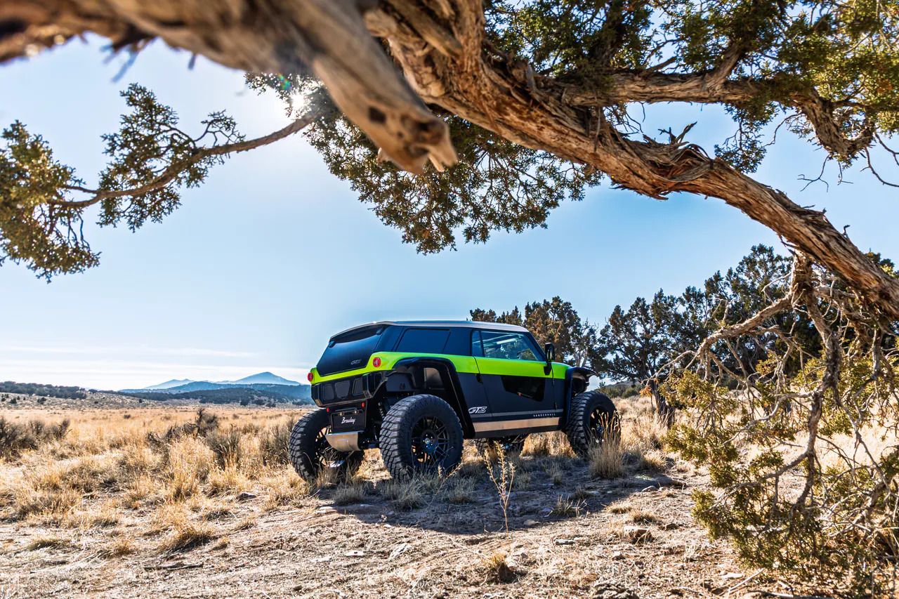 A Vanderhall Brawley electric off-road vehicle under a juniper tree
